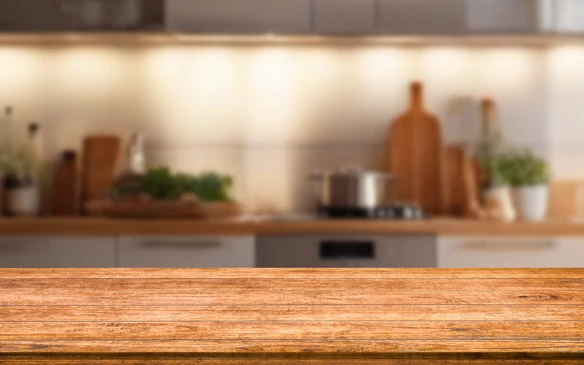 Cuisine moderne avec plan de travail en bois au premier plan, arri&egrave;re-plan flou montrant des &eacute;l&eacute;ments culinaires et &eacute;lectrom&eacute;nager int&eacute;gr&eacute;