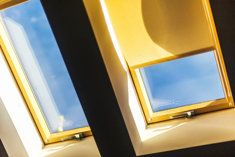 Intérieur mansardé avec deux fenêtres de toit ouvertes laissant entrer la lumière naturelle