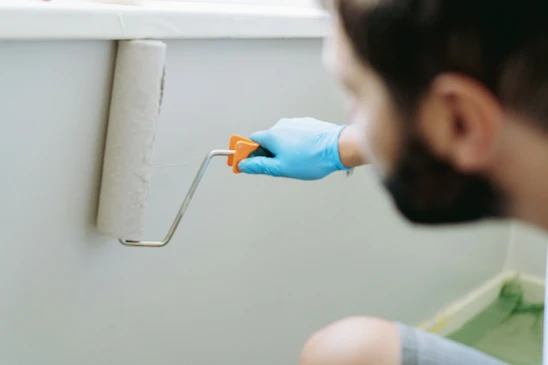 Int&eacute;rieur professionnel avec peintre appliquant de la peinture blanche sur un mur &agrave; l'aide d'un rouleau