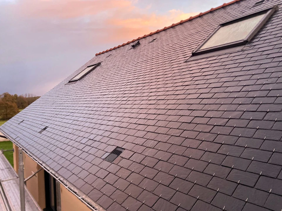 Ouvrier en bâtiment installant un panneau d'isolation thermique extérieure sur façade de maison en construction