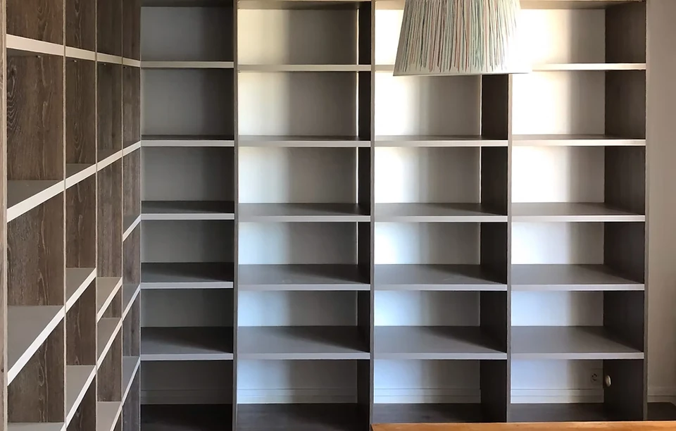 Chambre moderne avec dressing ouvert intégré au mur, présentant vêtements suspendus sur deux niveaux et chaussures rangées