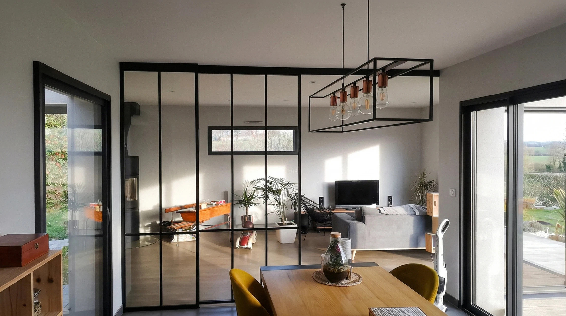 Espace de vie moderne en open space, s&eacute;par&eacute; par une verri&egrave;re atelier &agrave; profil&eacute;s acier noirs et vitrage clair