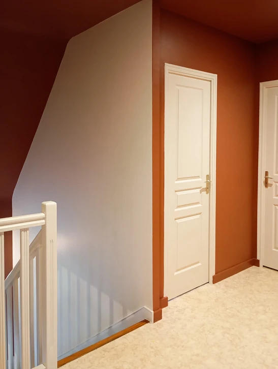 Rénovation d'appartement en cours avec peinture murale turquoise appliquée sur la moitié droite d'une pièce aux moulures décoratives