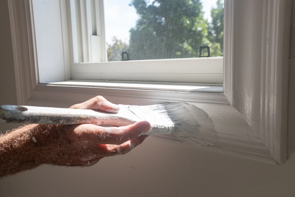 Professionnel peintre homme, se tient dans un appartement armé d'une brosse à rouleaux et seau lors d'une rénovation